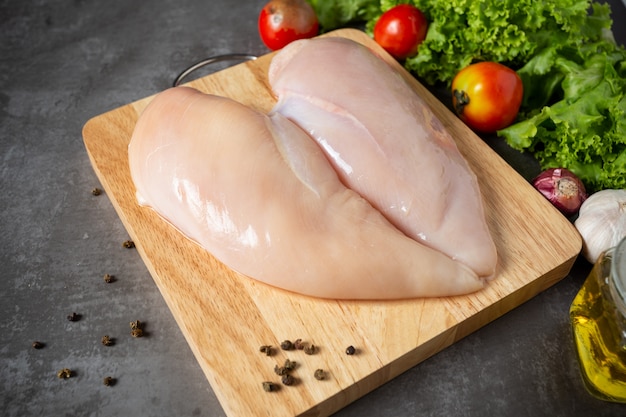 Free Photo raw chicken breasts on wooden cutting board.