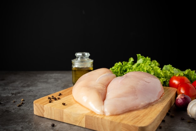 Free Photo raw chicken breasts on wooden cutting board.