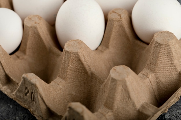 Free photo raw chicken eggs in egg box on a marble surface.