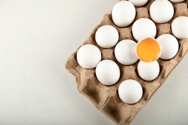 Free photo raw chicken eggs in egg box on a white surface.