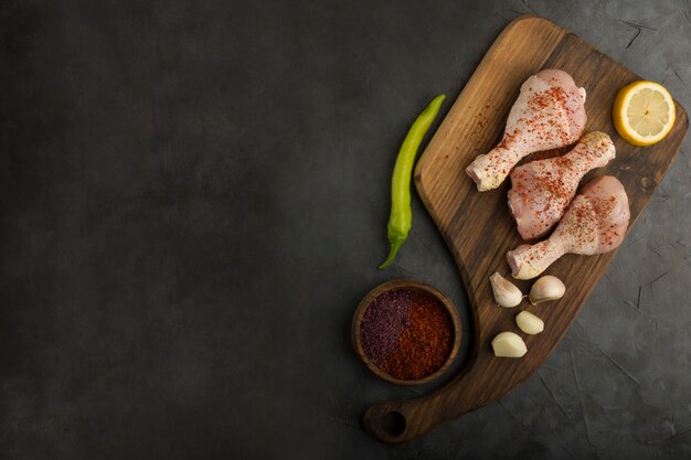 Raw chicken legs served with sauces and lemon