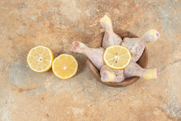 Free photo raw chicken legs with sliced lemon on marble surface