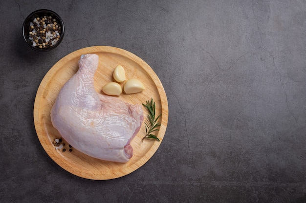 Raw chicken thighs on the dark wooden surface.