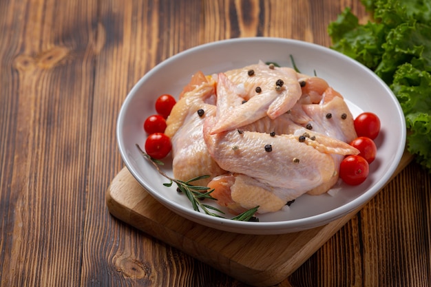 Raw chicken wings on the dark wooden surface.