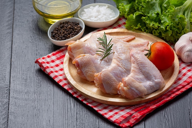 Raw chicken wings on the dark wooden surface.