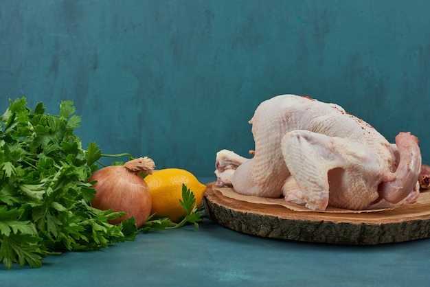 Raw chicken on a wooden board with herbs.