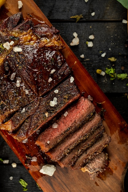 Raw cooked meat steak sliced and salt added, served on the black table