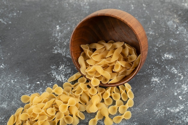 Raw dry farfalle tonde macaroni on a marble table . 