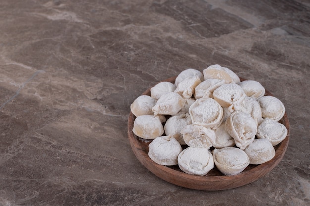 Raw dumplings on wooden board .