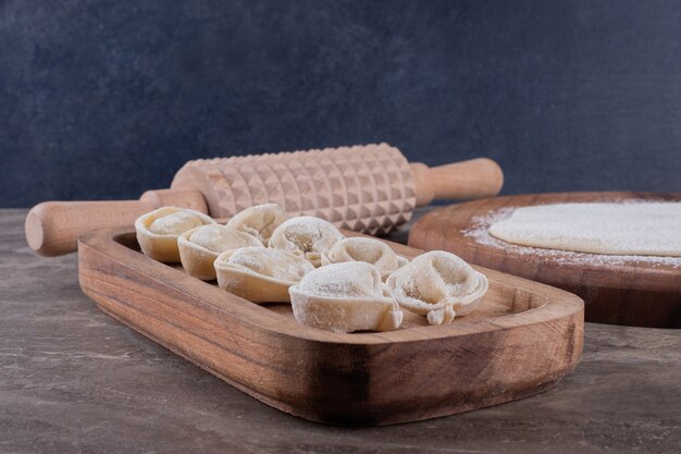 Raw dumplings on wooden board .