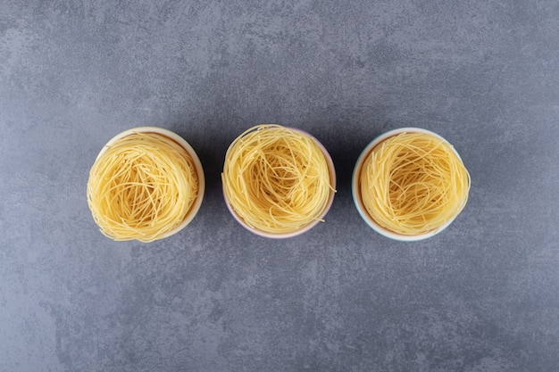 Raw egg noodles in colorful bowls.