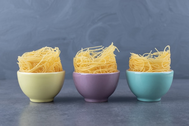 Free photo raw egg noodles in colorful bowls.