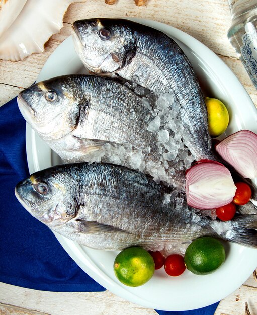 raw fish placed on plate with lime onion cherry tomato and ice