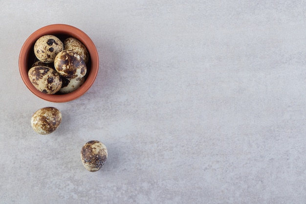 Raw fresh quail eggs placed on a stone background.