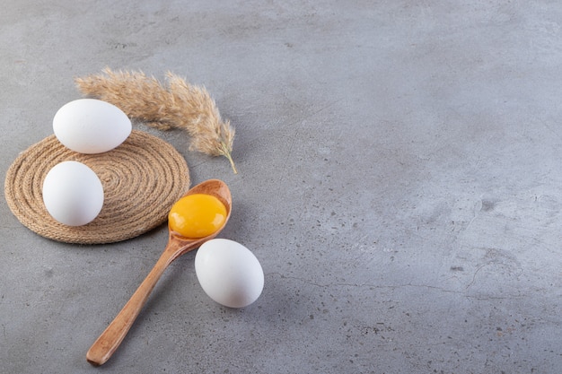 Free photo raw fresh white chicken eggs placed on a stone background.