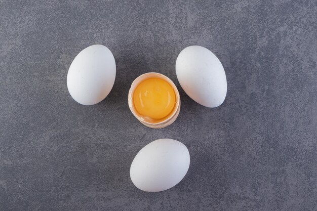 Raw fresh white chicken eggs placed on a stone surface. 