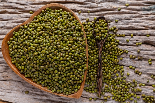 Free photo raw green beans in a cup placed on a wooden floor.