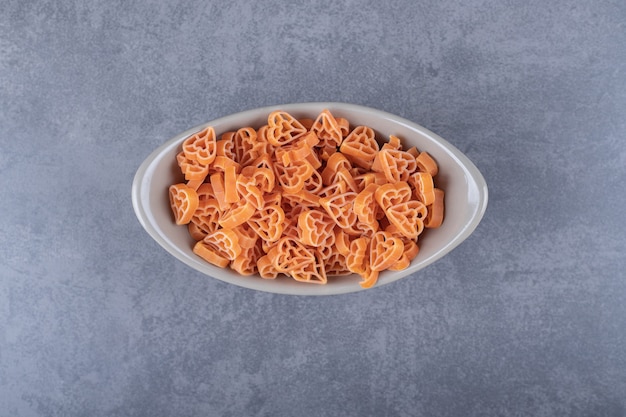 Free Photo raw heart-shaped pasta in ceramic bowl.