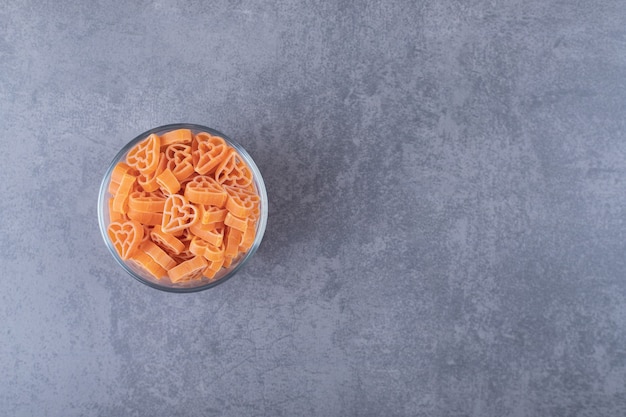 Free photo raw heart-shaped pasta in glass bowl.