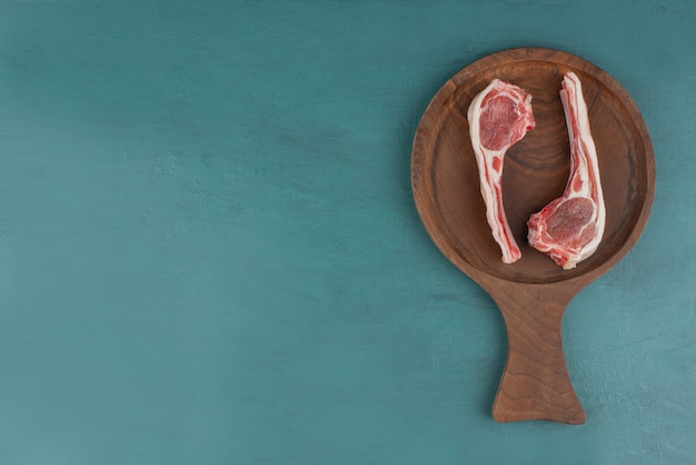 Free photo raw lamb chops on wooden board.