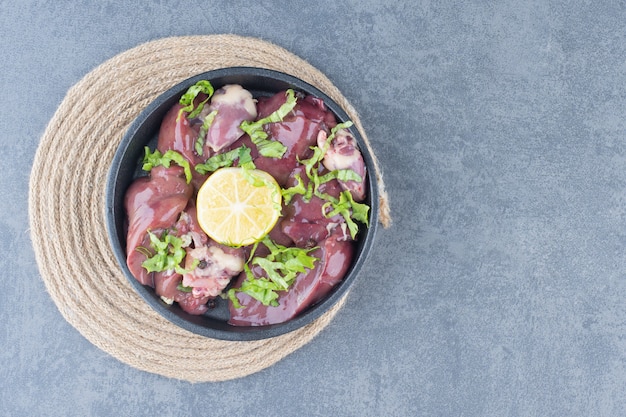 Free photo raw meat slices and sliced lemon on black plate.