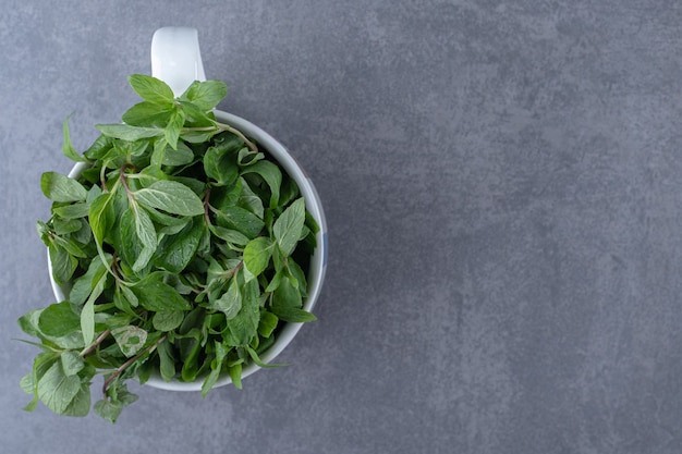 Raw mint in a cup , on the marble surface.