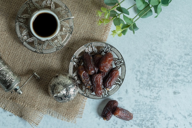 Raw organic dates on glass saucer with cup of coffee.