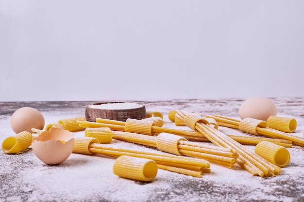 Raw pasta with flour and eggs onwooden table. 