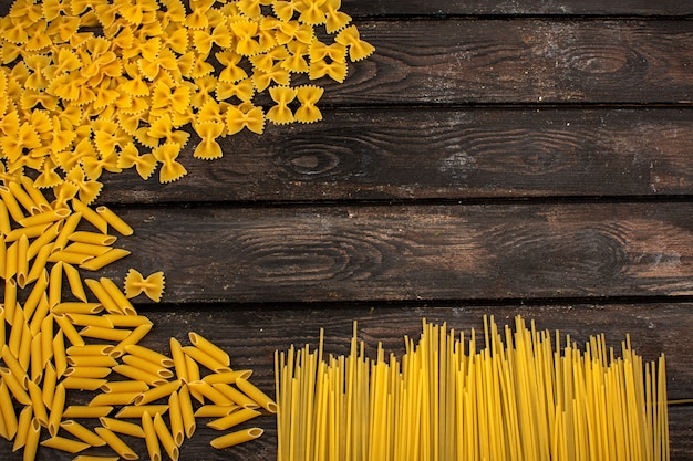 Raw pasta yellow different shaped on a brown wooden rustic table