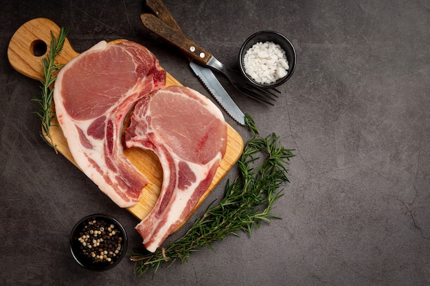 Raw pork chop steak on the dark surface.