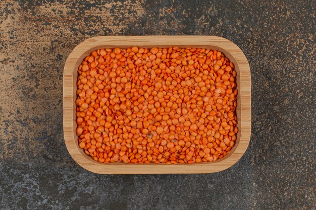 Raw red lentils on wooden plate. 