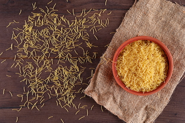 Free Photo raw soup pasta in ceramic bowl top view on sackcloth