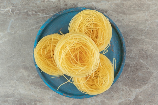 Raw spaghetti nests on blue plate