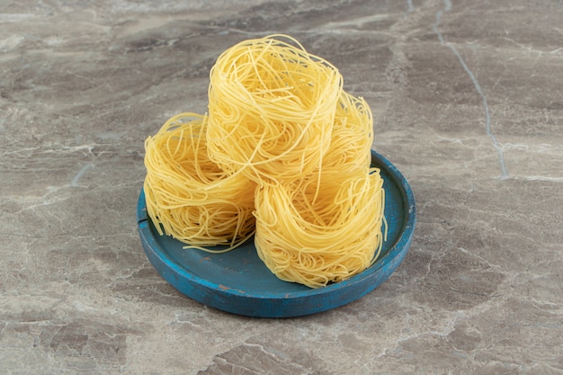 Raw spaghetti nests on blue plate