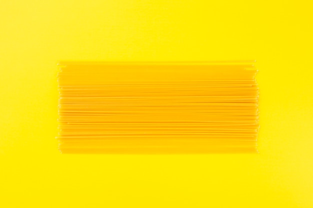 Raw spaghetti on yellow background