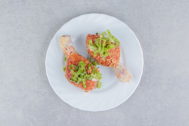 Raw spicy chicken legs in the plate, on the white surface