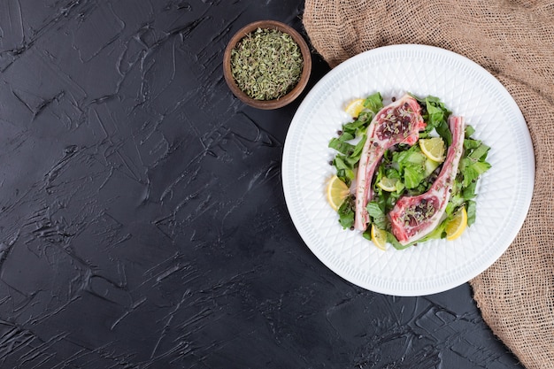 Free Photo raw two beef chops on white plate with lemon slices and green.