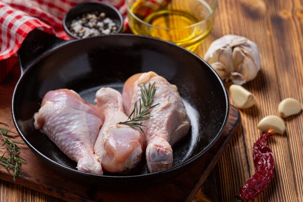 Raw uncooked chicken legs on the dark wooden surface.