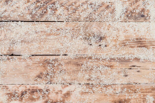 Raw white rice scattered over textured wooden surface