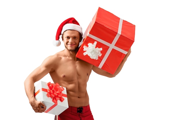 Ready to celebrate. Sexy attractive guy wearing Santa Claus hat smiling holding presents showing off his ripped body