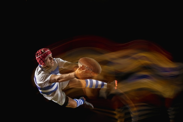 Free Photo ready to fly for win. one caucasian man playing rugby on the stadium in mixed light.