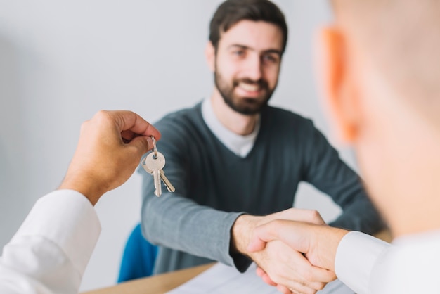 Free photo real estate agent shaking hand of client and holding keys