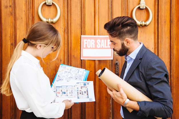 Real estate agents waiting with plans in front of door