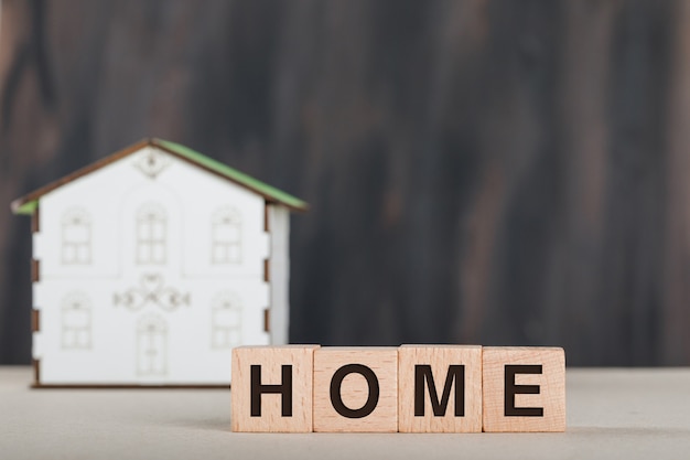 Real estate concept with wooden cubes, house model and white.