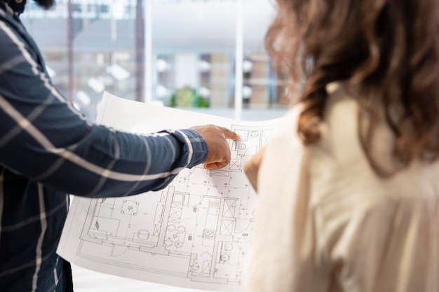 Free Photo real estate expert presenting office space layout to woman using blueprints