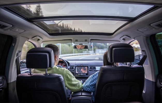 Free photo rear back view from passenger seat of man and lady sitting inside car