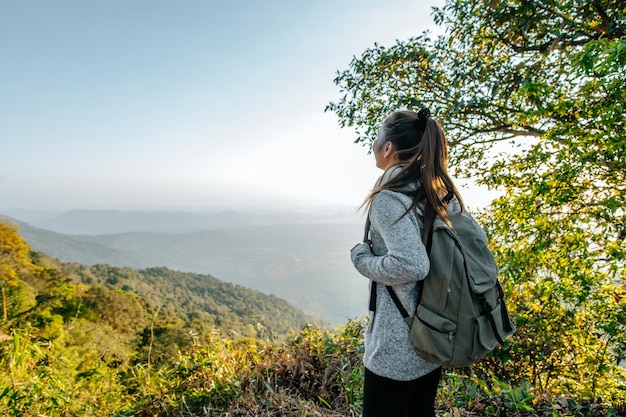 Rear view back of Young asian hiking female standing at view point and looking beautiful view with happy on peak mountain and sunray  copy space