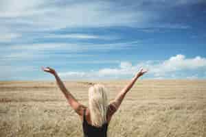 Free photo rear view of blonde woman standing in field