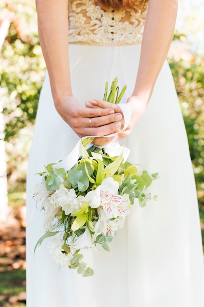 Rear view of a bride with hand behind her back holding flower bouquet