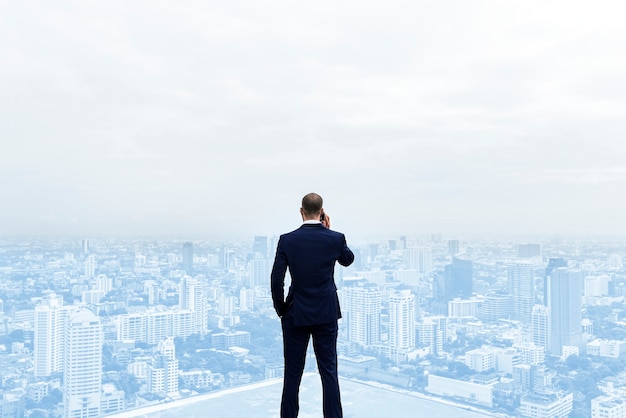 Rear view of a businessman talking on the phone on top of the building